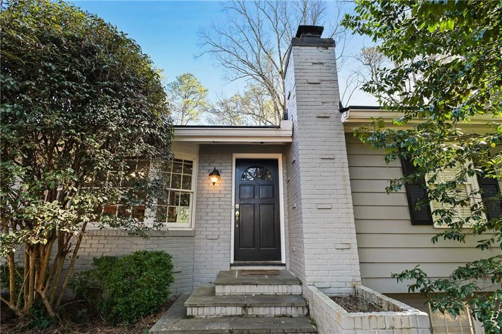 Doorway to property featuring a chimney and brick siding