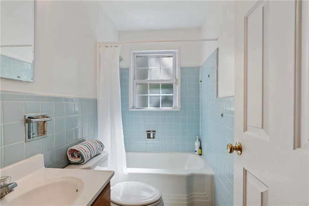 Bathroom featuring toilet, vanity, tile walls, and shower / tub combo with curtain