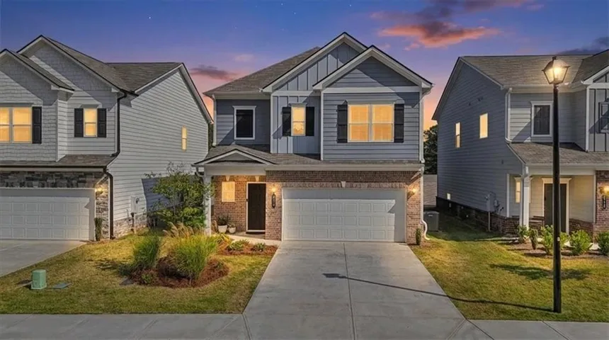 Two-story residence with a single-car garage, brick and siding exterior, concrete driveway, and covered entry