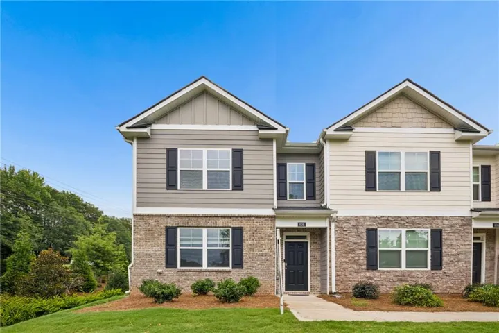 Contemporary townhome exterior featuring a mixed material facade, gabled rooflines, and dark window shutters