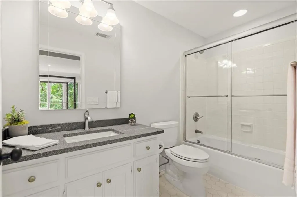 Full bathroom featuring vanity, toilet, tile flooring, and enclosed tub / shower combo Full bathroom featuring vanity, toilet, tile flooring, and enclosed tub / shower combo