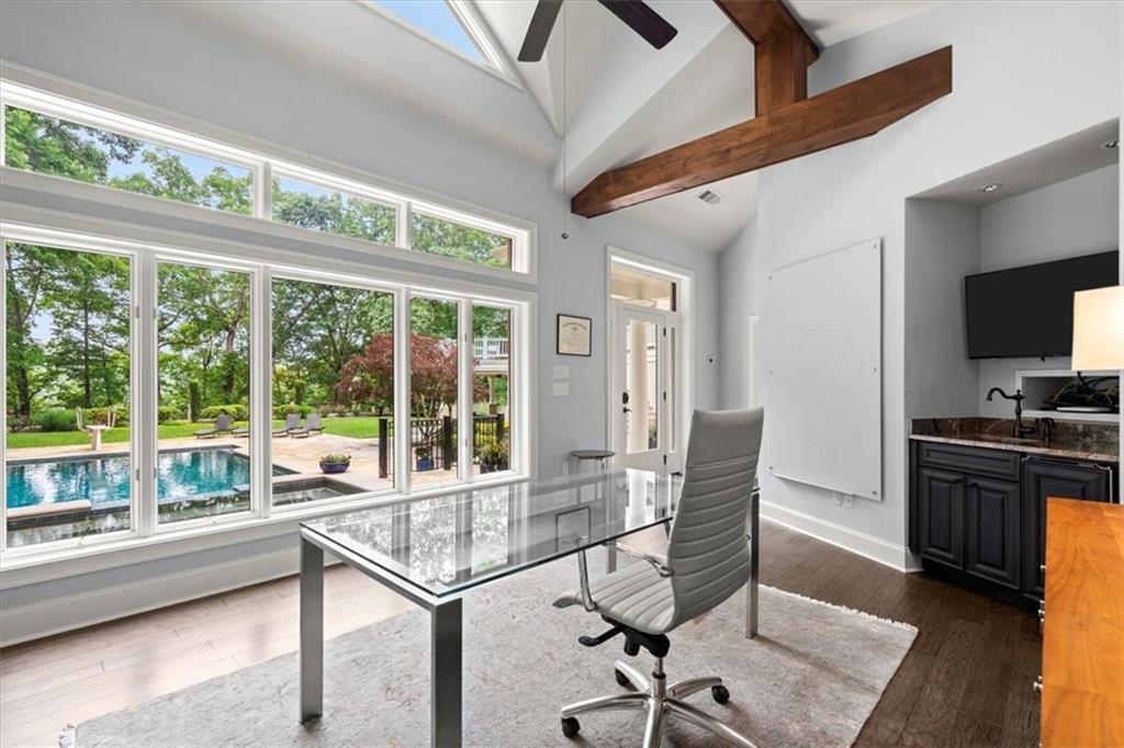 Office space featuring beam ceiling, high vaulted ceiling, dark wood-type flooring, and ceiling fan Office space featuring beam ceiling, high vaulted ceiling, dark wood-type flooring, and ceiling fan