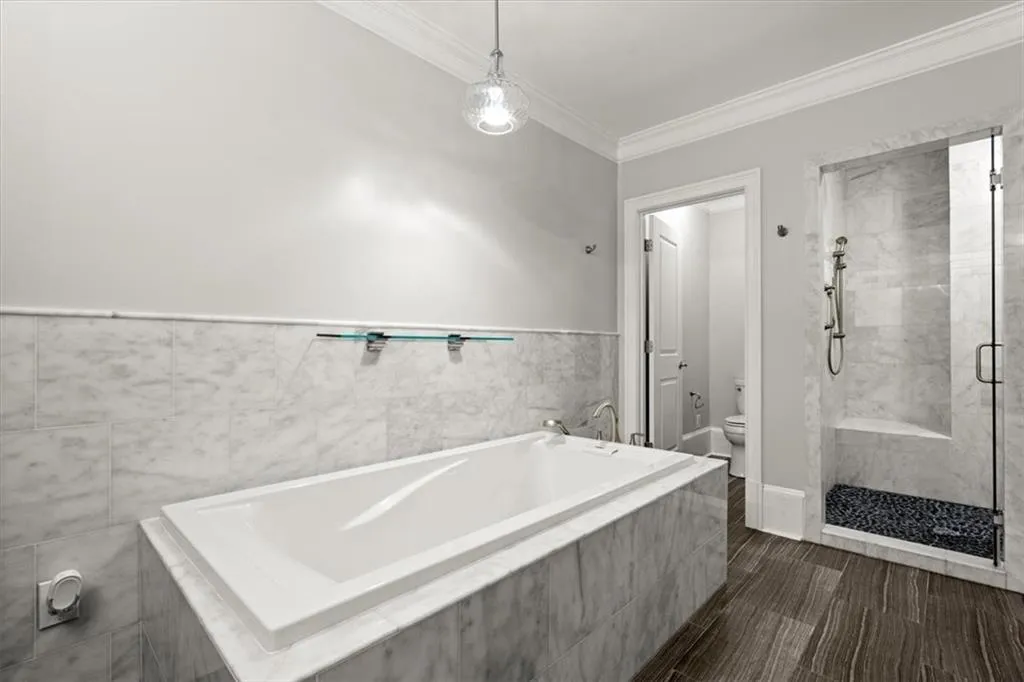 Bathroom with crown molding, toilet, plus walk in shower, and hardwood / wood-style flooring Bathroom with crown molding, toilet, plus walk in shower, and hardwood / wood-style flooring