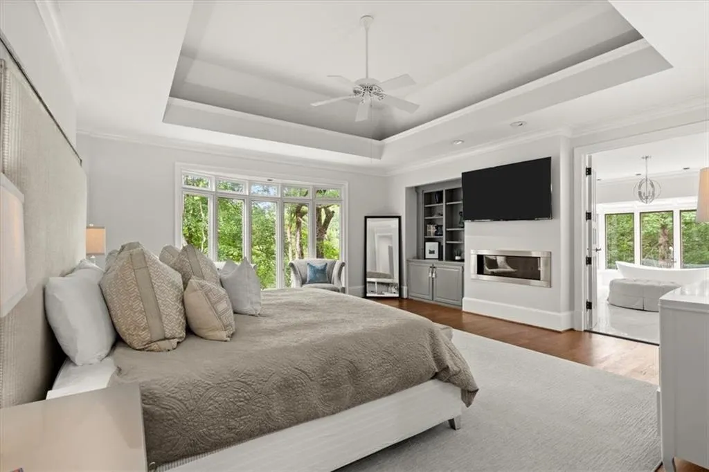 Bedroom with multiple windows, a tray ceiling, and ceiling fan with notable chandelier Bedroom with multiple windows, a tray ceiling, and ceiling fan with notable chandelier