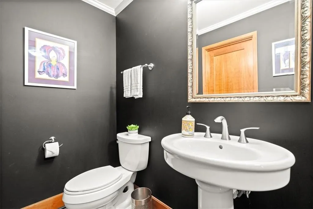 Bathroom featuring crown molding, toilet, and sink Bathroom featuring crown molding, toilet, and sink