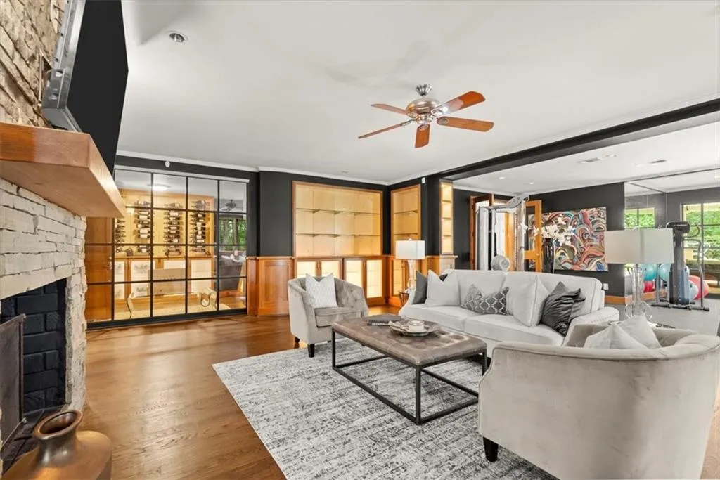 Living room featuring a wall of windows, a stone fireplace, light hardwood / wood-style flooring, and ceiling fan Living room featuring a wall of windows, a stone fireplace, light hardwood / wood-style flooring, and ceiling fan