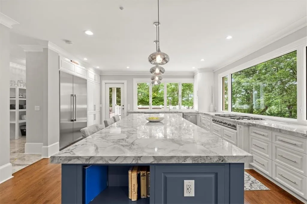 Kitchen with stainless steel appliances, dark hardwood / wood-style floors, a center island, and white cabinetry Kitchen with stainless steel appliances, dark hardwood / wood-style floors, a center island, and white cabinetry