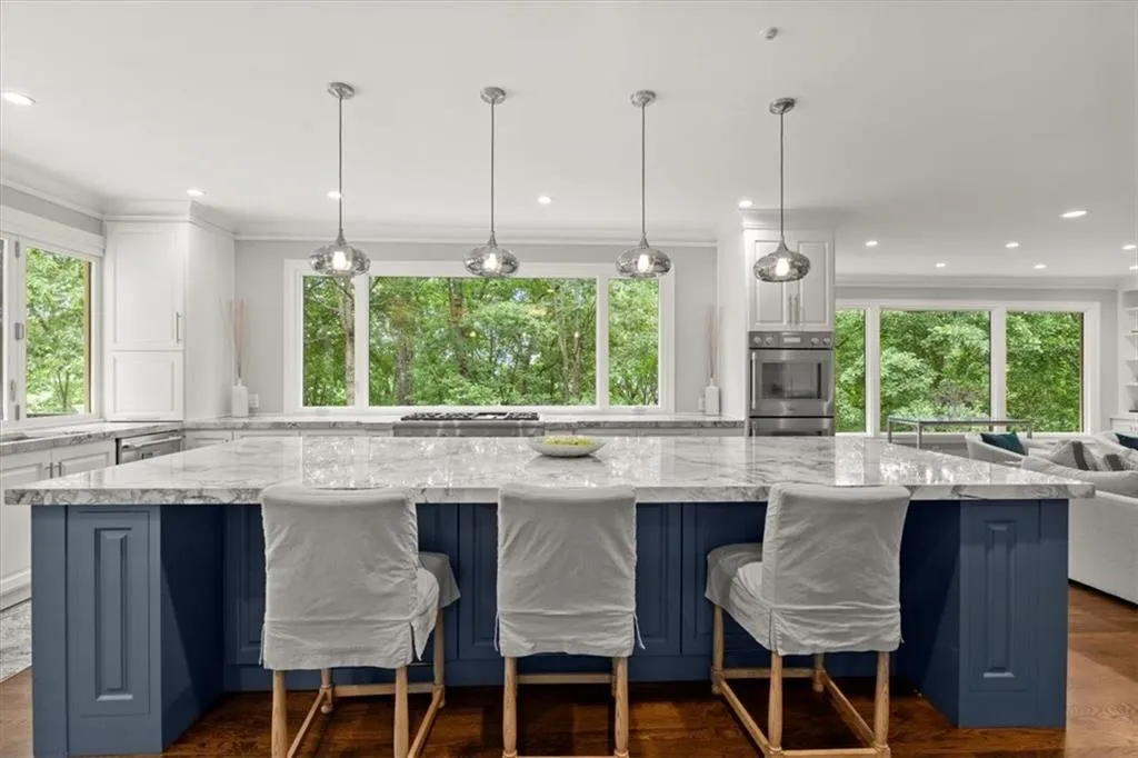 Kitchen featuring decorative light fixtures, white cabinets, stainless steel appliances, and light stone counters Kitchen featuring decorative light fixtures, white cabinets, stainless steel appliances, and light stone counters