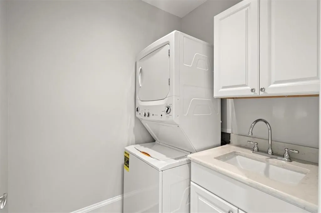 Washroom featuring cabinets, sink, and stacked washer / dryer Washroom featuring cabinets, sink, and stacked washer / dryer