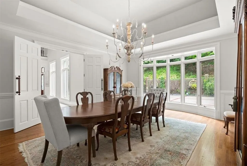 Dining room featuring a chandelier, a raised ceiling, and light hardwood / wood-style flooring Dining room featuring a chandelier, a raised ceiling, and light hardwood / wood-style flooring