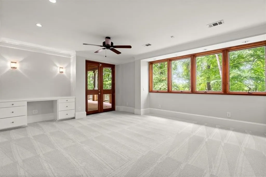 Carpeted spare room featuring built in desk, ornamental molding, and ceiling fan Carpeted spare room featuring built in desk, ornamental molding, and ceiling fan