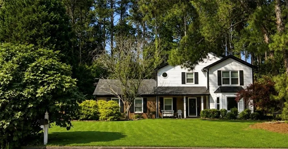 Two-story exterior with white siding and black shutters, featuring a covered front porch