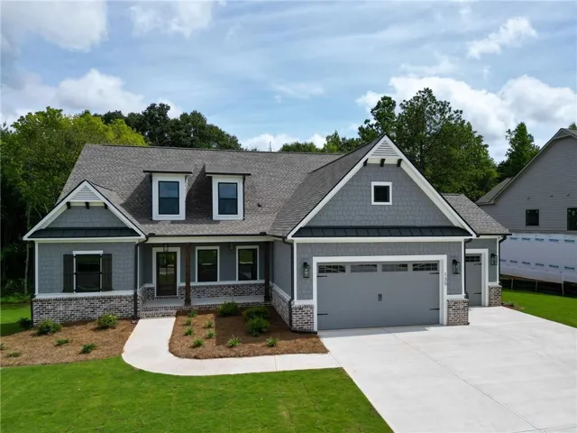 Craftsman-style home featuring a covered front porch with exposed beam accents, a two-car garage, and a single-car garage