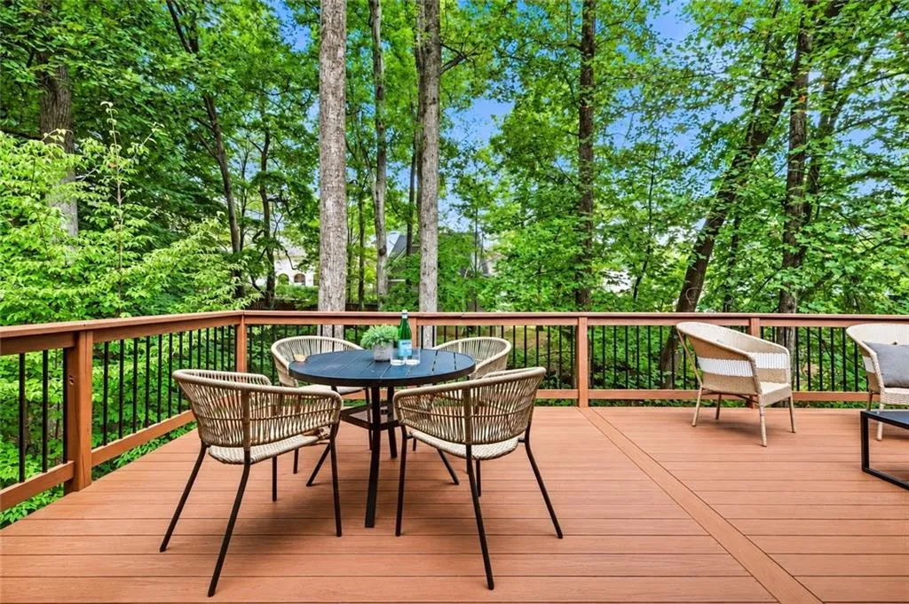 Elevated wooden deck featuring metal balusters and mature tree surrounds