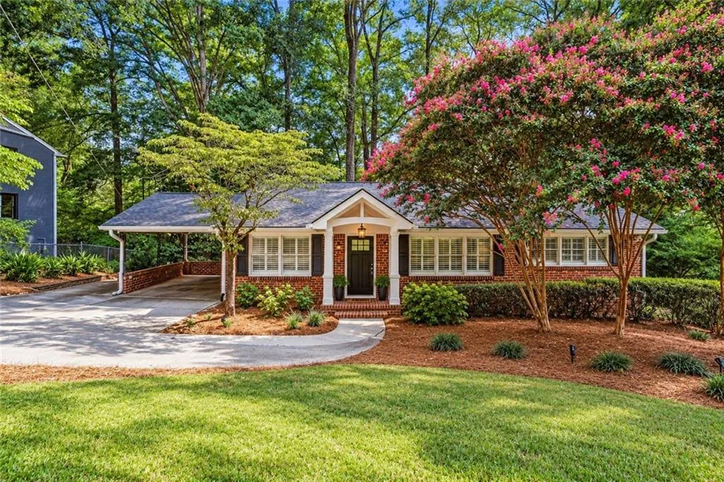 Single-story brick exterior featuring a covered carport, gabled entryway with decorative support beams, multi-pane windows, and manicured landscaping