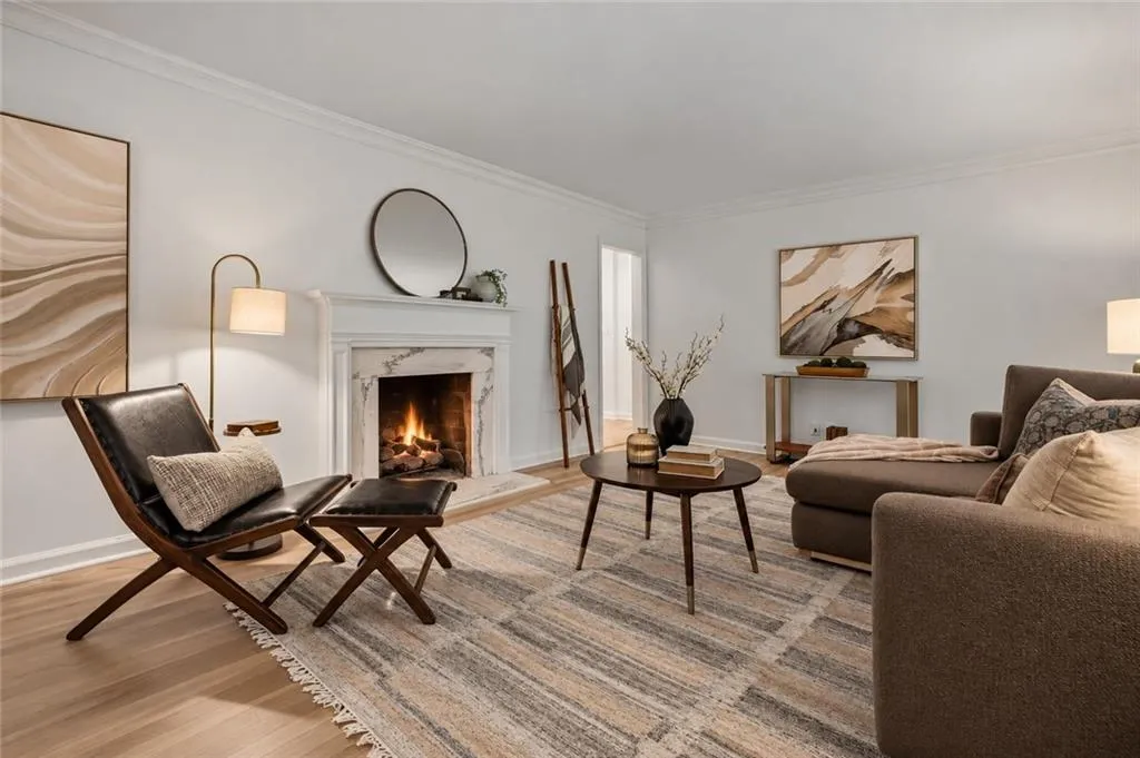 Fireplace with stone-patterned surround, crown molding, and wood-finish flooring