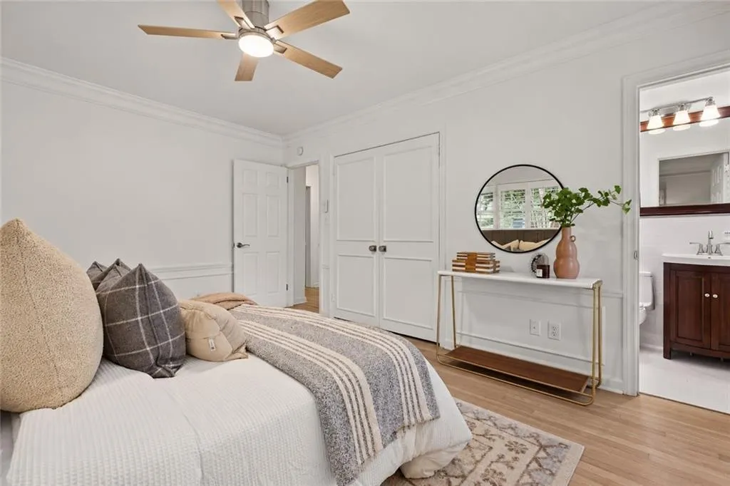 Interior space featuring wood-finish flooring, crown molding, double-panel closet doors, and a ceiling fan with integrated lighting