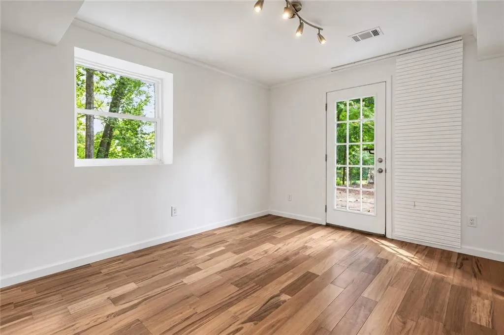 Interior space featuring wood-finish flooring, a multi-pane glass door, horizontal blinds, and a multi-bulb track lighting fixture