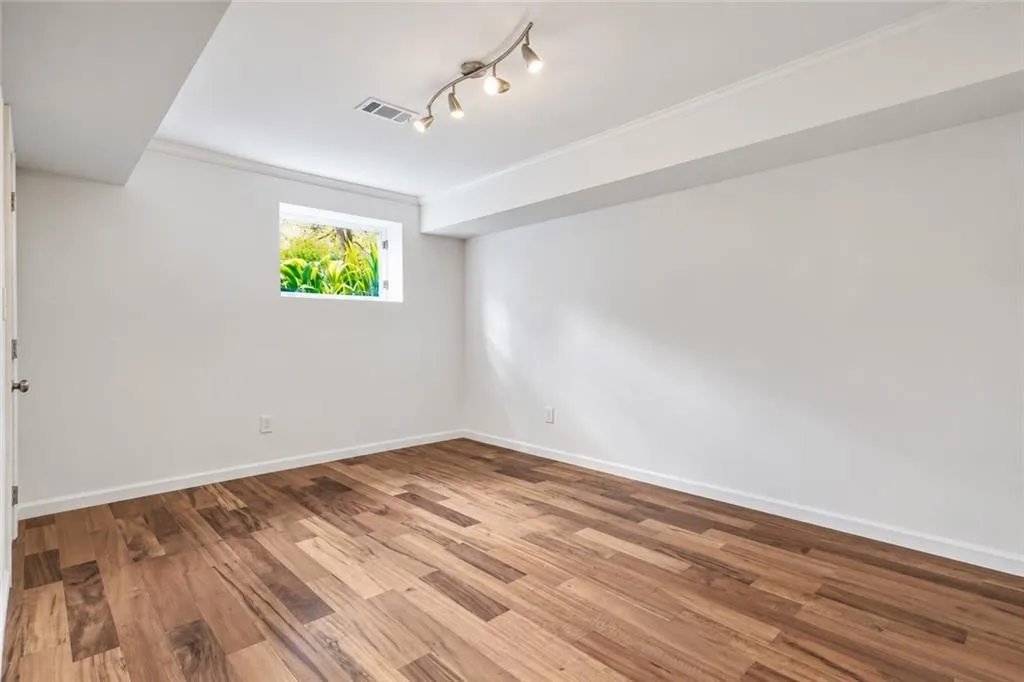 Room featuring wood-finish flooring, recessed wall window, and ceiling-mounted adjustable track lighting