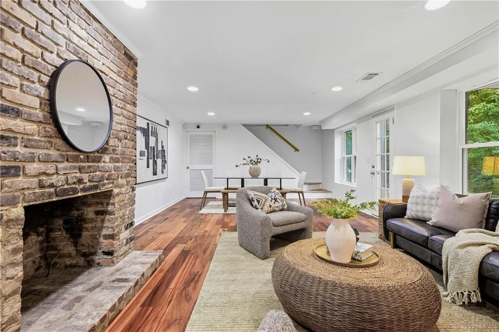 Expansive interior featuring exposed brick fireplace, wood-finish flooring, recessed lighting, and crown molding
