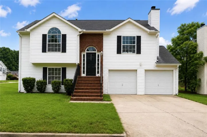 Traditional two-story residence featuring white siding and brick accents