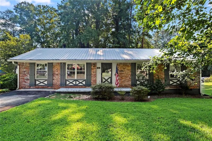 Brick Exterior With A Metal Roof, Featuring decorative window Shutters And A Well Manicured Lawn
