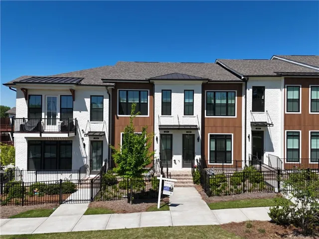 Contemporary townhome facade featuring white stucco, wood-finish siding, and black-framed windows