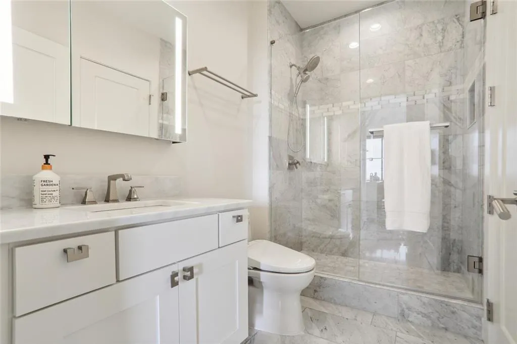 Bathroom with toilet, a stall shower, and vanity