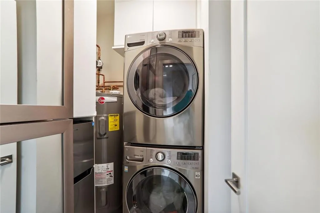 Washroom with laundry area, stacked washer and dryer, and electric water heater