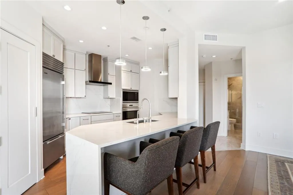 Kitchen with visible vents, a sink, wall chimney range hood, a peninsula, and black appliances