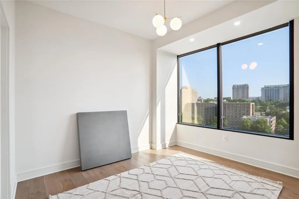 Spare room with baseboards, a notable chandelier, wood finished floors, and a city view