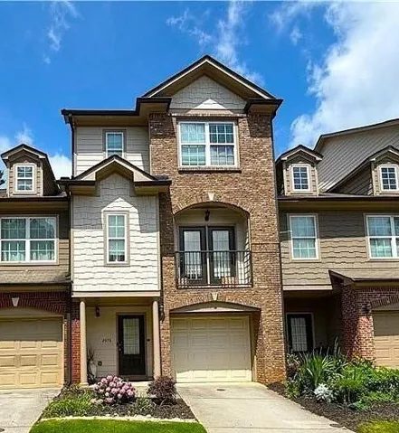 Townhome / multi-family property featuring a balcony, a garage, and brick siding