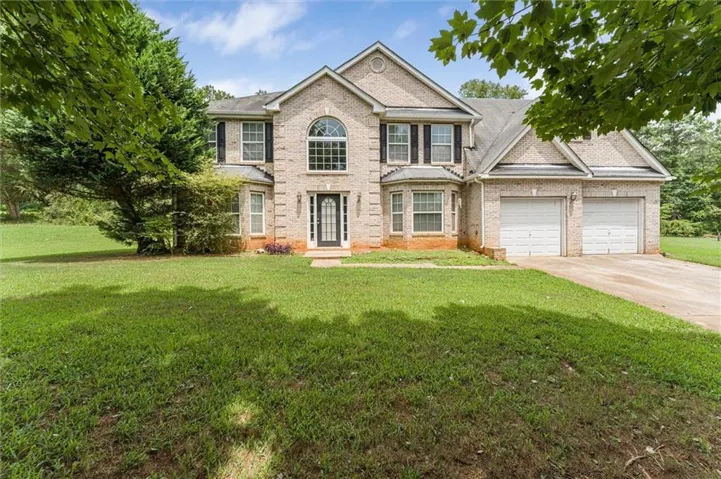 Traditional-style residence featuring a brick facade, two-story design, and prominent arched window above the main entrance