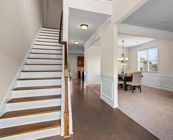 Hardwood flooring, painted wainscoting, crown molding, staircase with wood treads, recessed lighting