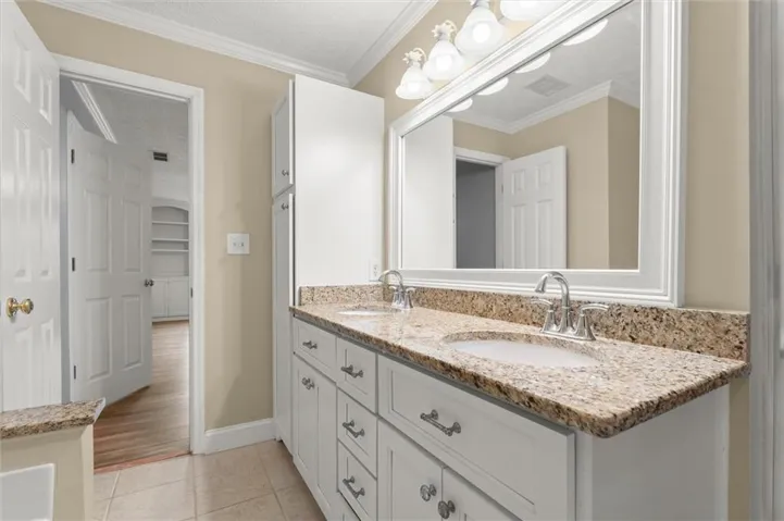 Dual vanity with granite countertops and integrated sinks, white cabinetry, and matching framed mirror