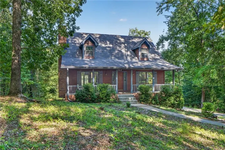 Wood-sided facade with a covered porch, white railing, and two dormer windows