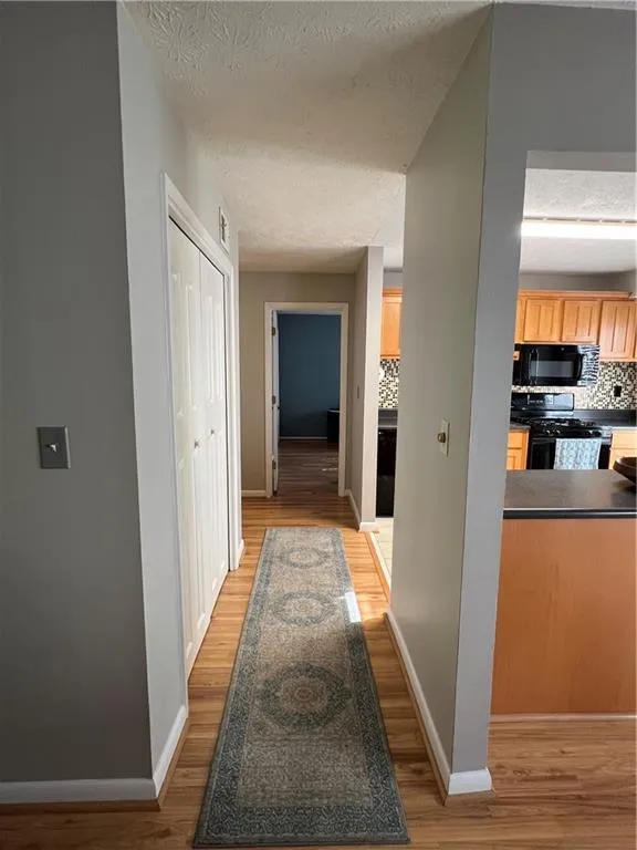 Corridor featuring light hardwood / wood-style flooring and a textured ceiling