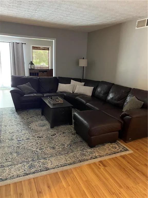 Living room with light wood-type flooring and a textured ceiling