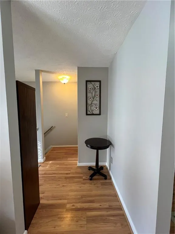 Corridor featuring light wood-type flooring and a textured ceiling