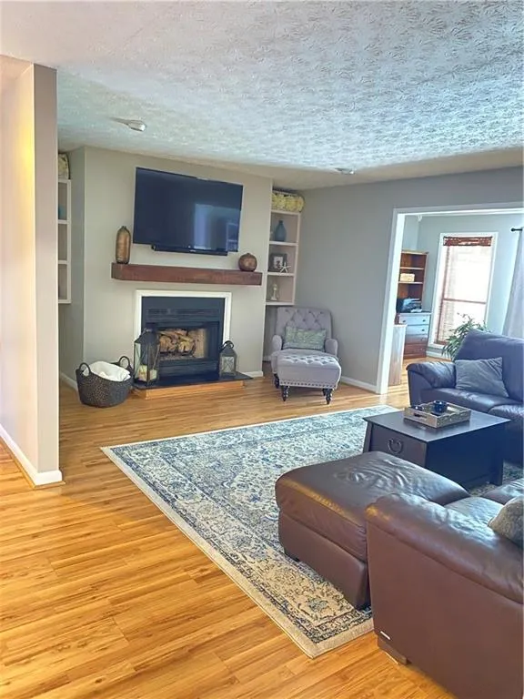 Living room featuring built in features, light hardwood / wood-style floors, and a textured ceiling