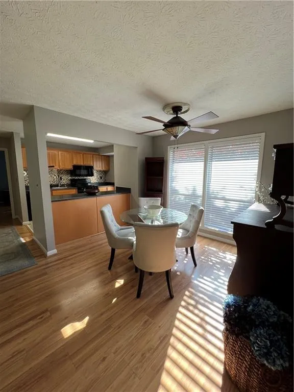 Dining space featuring a textured ceiling, ceiling fan, and light wood-type flooring
