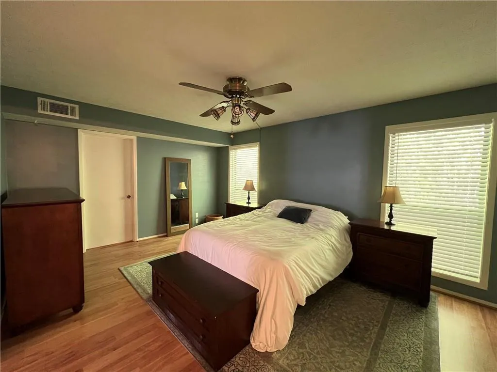 Bedroom with hardwood / wood-style floors, multiple windows, and ceiling fan