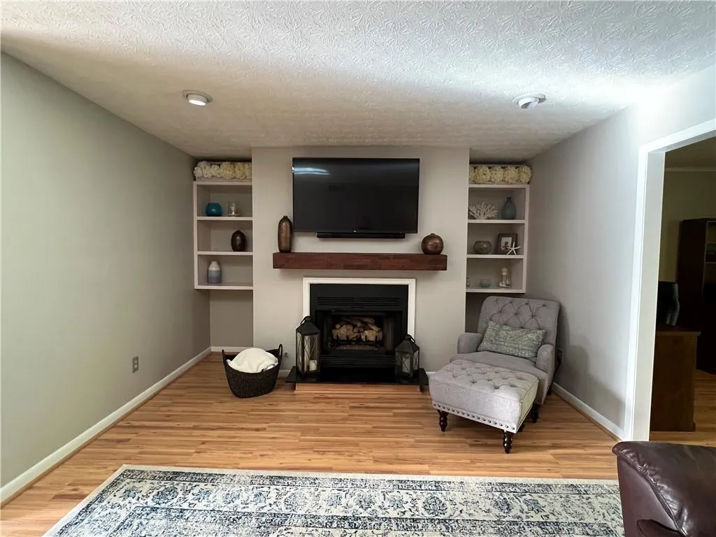 Sitting room featuring built in shelves, light hardwood / wood-style flooring, and a textured ceiling
