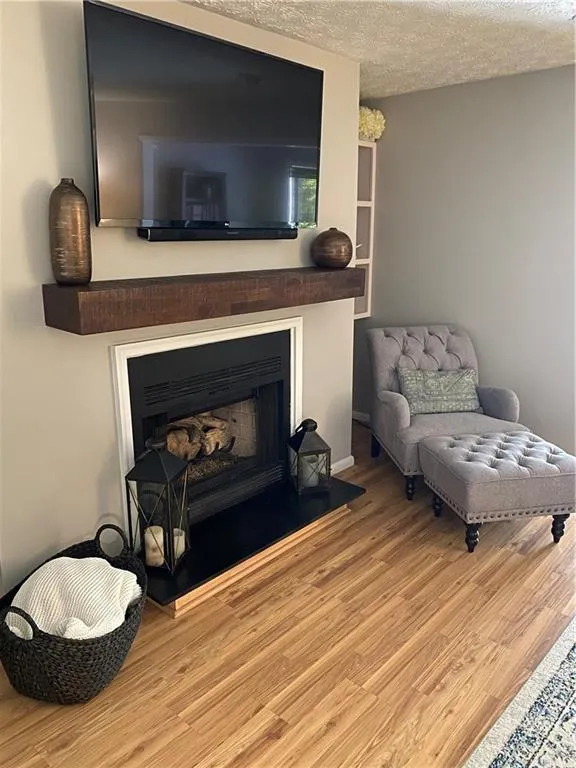 Sitting room with a textured ceiling and light hardwood / wood-style floors