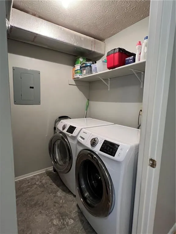 Clothes washing area with a textured ceiling, washer and dryer, and dark tile floors