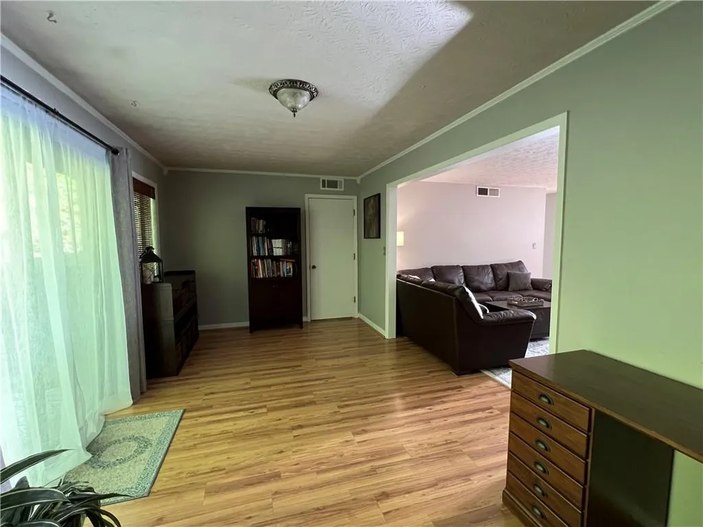 Hallway with light hardwood / wood-style flooring, a textured ceiling, and ornamental molding