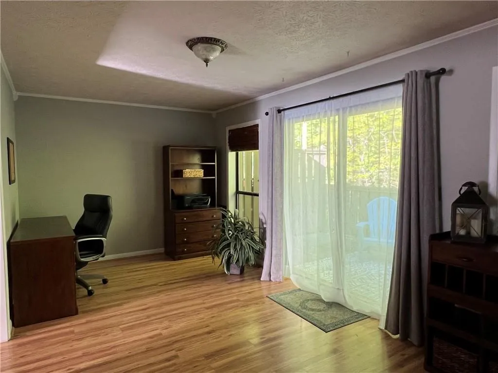 Office space featuring a textured ceiling, crown molding, and light wood-type flooring