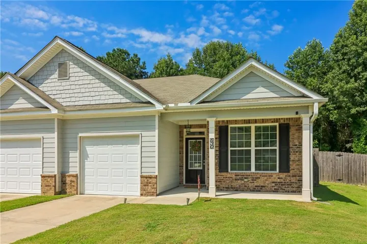 Exterior features include a covered front entry, brick and siding facade, dual garage doors, and a manicured lawn