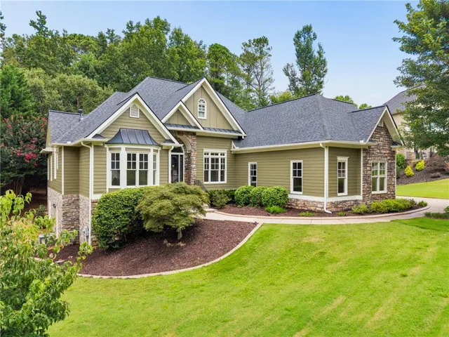 Two-story residence featuring a gable roof, siding exterior, stone accents, and a bay window