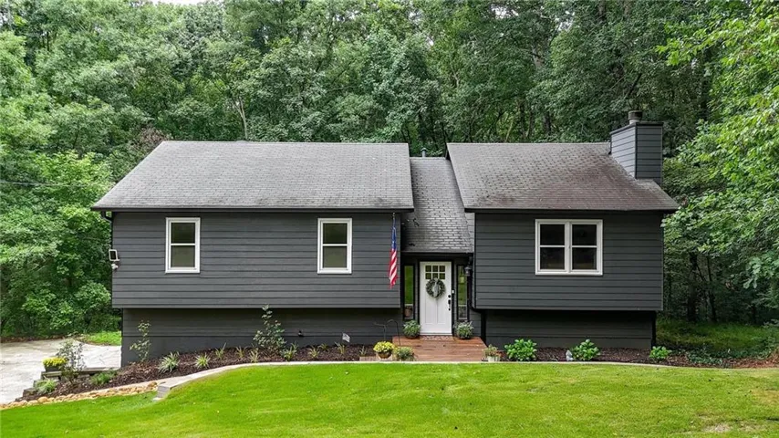 Contemporary split-level residence featuring dark gray siding and white trim windows